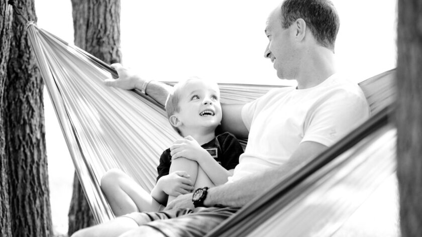 A lovely moment between father and son in a hammock, showcasing family bonding and happiness.