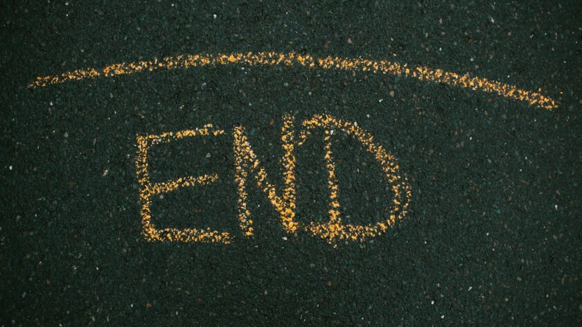 Close-up of 'END' written on asphalt with yellow chalk.