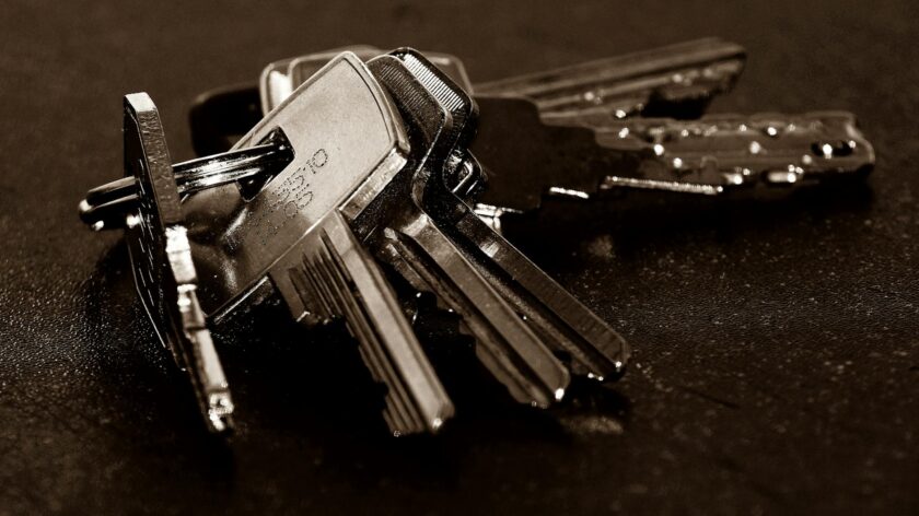 A detailed close-up of a bunch of metallic keys resting on a dark textured surface.