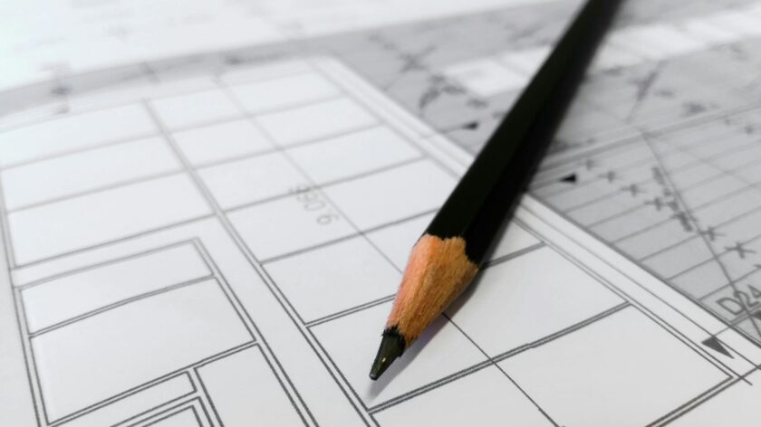 Detailed image of a black pencil resting on architectural blueprints, ideal for design and planning themes.