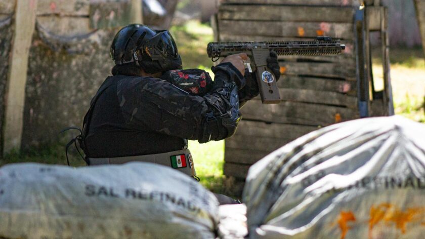 A player in protective gear engaged in a dynamic outdoor paintball match.