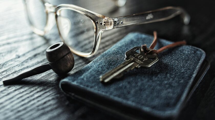 A detailed image of glasses, a key, and a pipe on a textured wooden table.