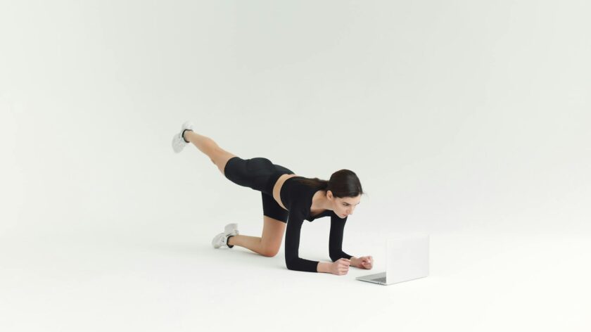 Woman in activewear working out in front of laptop on white background.