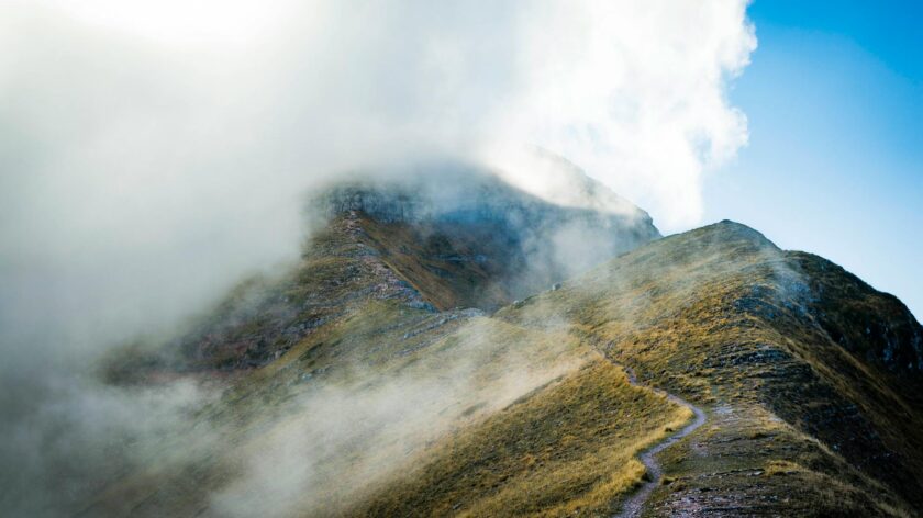 Explore the serene misty mountain landscape in Montemonaco, Italy, with a winding path and scenic views.