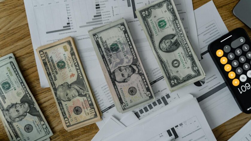 A workspace setup featuring cash, documents, and a calculator symbolizing financial analysis and budgeting.
