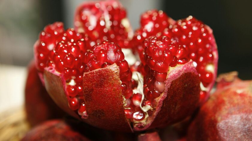 Detailed macro shot of a fresh, vibrant pomegranate exposing its juicy seeds.