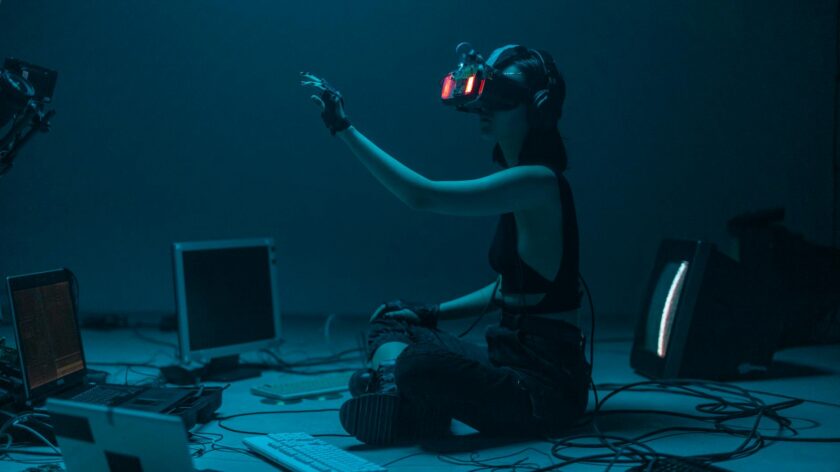 Woman immersed in virtual reality, surrounded by tech, in a dimly lit room.