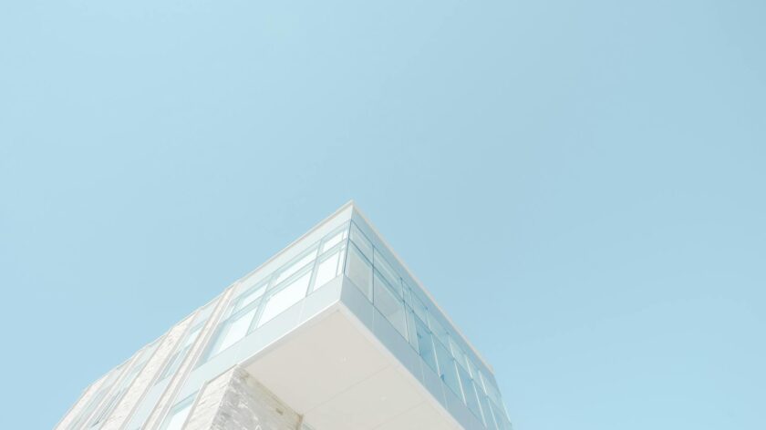 A low-angle shot of a modern building with a glass facade against a bright blue sky in London, Canada.